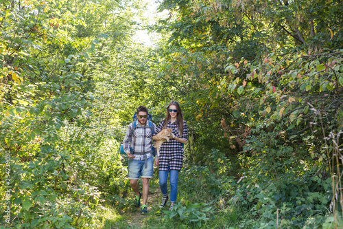 Travel, adventures, hike, tourism and nature concept - Tourist couple with cat walking in the woods