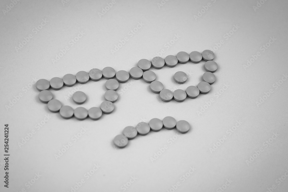 Black and white photo of Face with glasses made of pink pills on pink background with vignette effect. Concept of eyesight and depression. Black and white photo of Face with glasses made of pink pills on pink background with vignette effect. Concept of eyesight and depression.