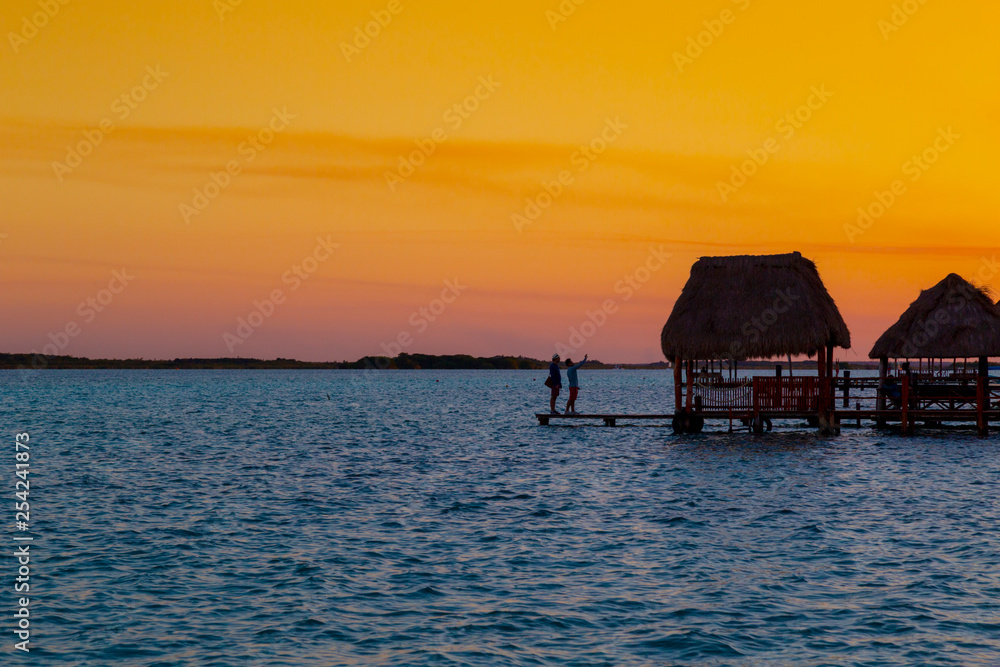 sunset in Lagoon of Seven Colors in Bacalar,couple watching the sun,Quintana Roo, México.