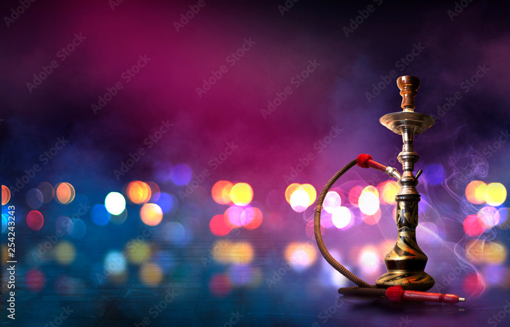 Hookah with smoke on the background of an empty scene, wet asphalt and colored neon light, blurry lights of the night city, bokeh Hookah with smoke on the background of an empty scene, wet asphalt and colored neon light, blurry lights of the night city, bokeh