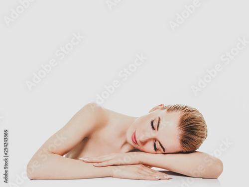 Woman lying her head on arms with closed eyes, on white background.