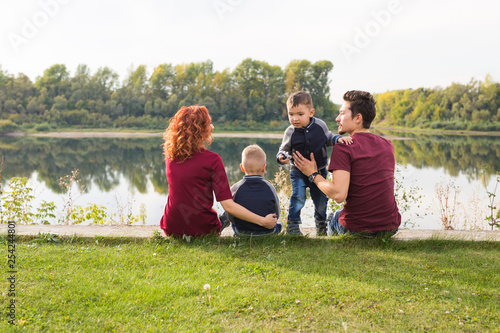 Childhood and nature concept - Family with little sons sitting on the green grass