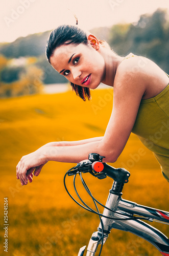 Fototapeta Naklejka Na Ścianę i Meble -  Young woman riding on bike through the country landscape in autumn.