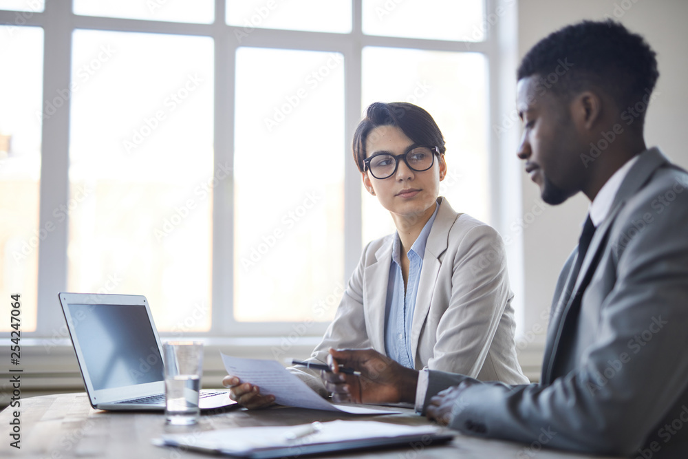 Obraz premium Young serious employee in formalwear listening to her colleague and looking at him during his explanations