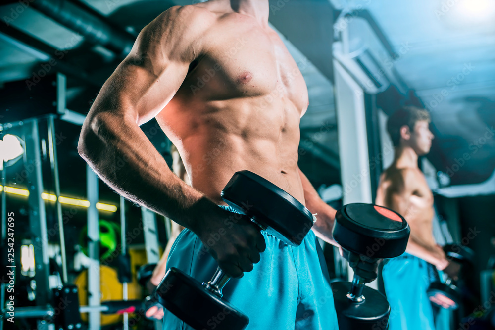 Naklejka premium closeup of dumbbells in the hands of fitness men bodybuilder