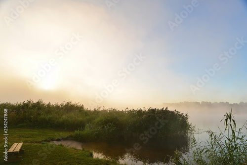 Bright light of the rising sun in the fog near the river