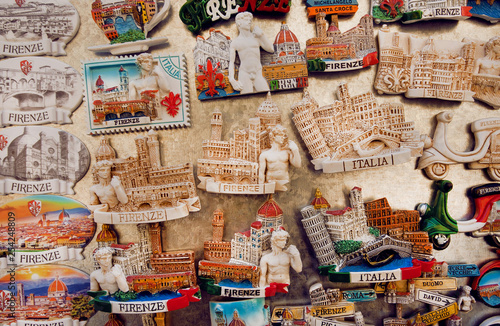 Many colorful magnets in souvenir store with symbols of Tuscany and local cities