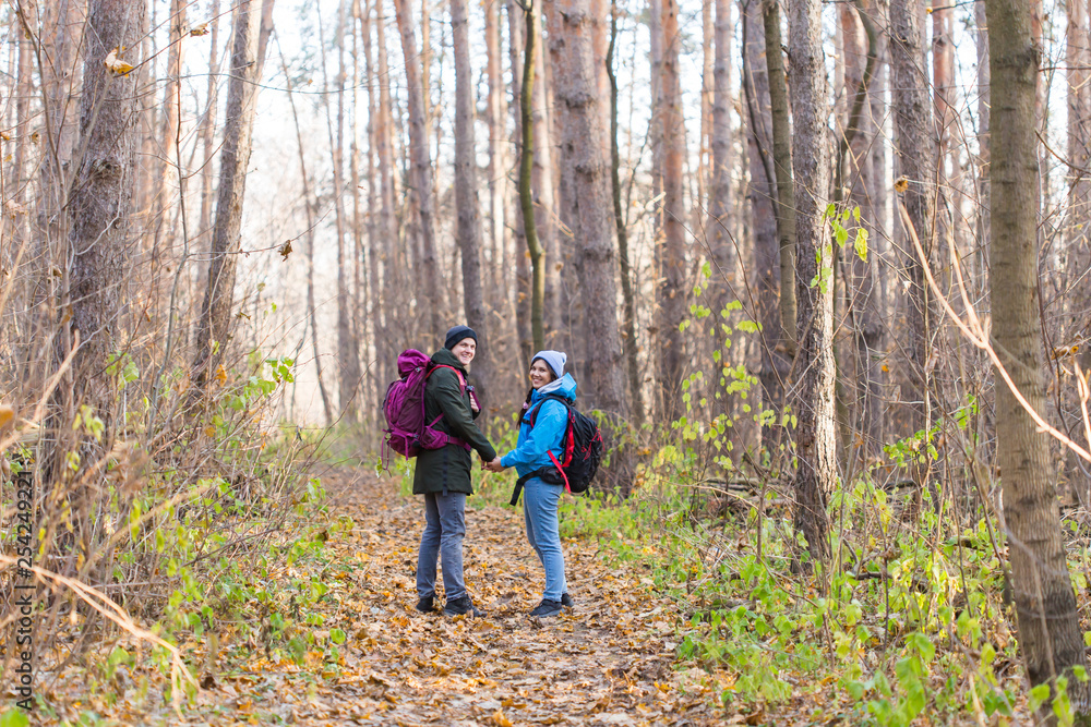 adventure, travel, tourism, hike and people concept - smiling couple walking with backpacks over autumn natural background adventure, travel, tourism, hike and people concept - smiling couple walking with backpacks over autumn natural background