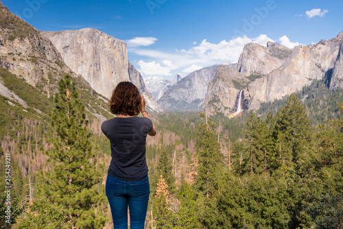 Young woman is taking a photo of Yosemite valley from Tunnel View in Yosemite National park, United states of America
