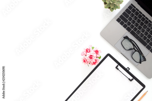 Creative flat lay photo of workspace desk. Top view office desk with laptop, glasses, pencil, blank clipboard and plant on white color background. Top view with copy space, flat lay photography.