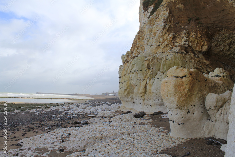 the beach along the white alabaster cliff coast in normandy, france at a stormy day with low tide