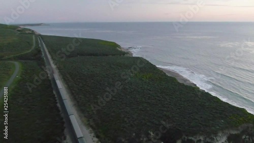 Amtrak passenger train traveling along coastline (aerial). photo