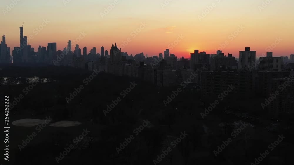 Epic drone slide over the top of New York City's Central Park at gorgeous sunset golden hour. Rotating view of the Upper East Side skyline while the gorgeous red sun stays as a focal point. in 4K. Epic drone slide over the top of New York City's Central Park at gorgeous sunset golden hour. Rotating view of the Upper East Side skyline while the gorgeous red sun stays as a focal point. in 4K.
