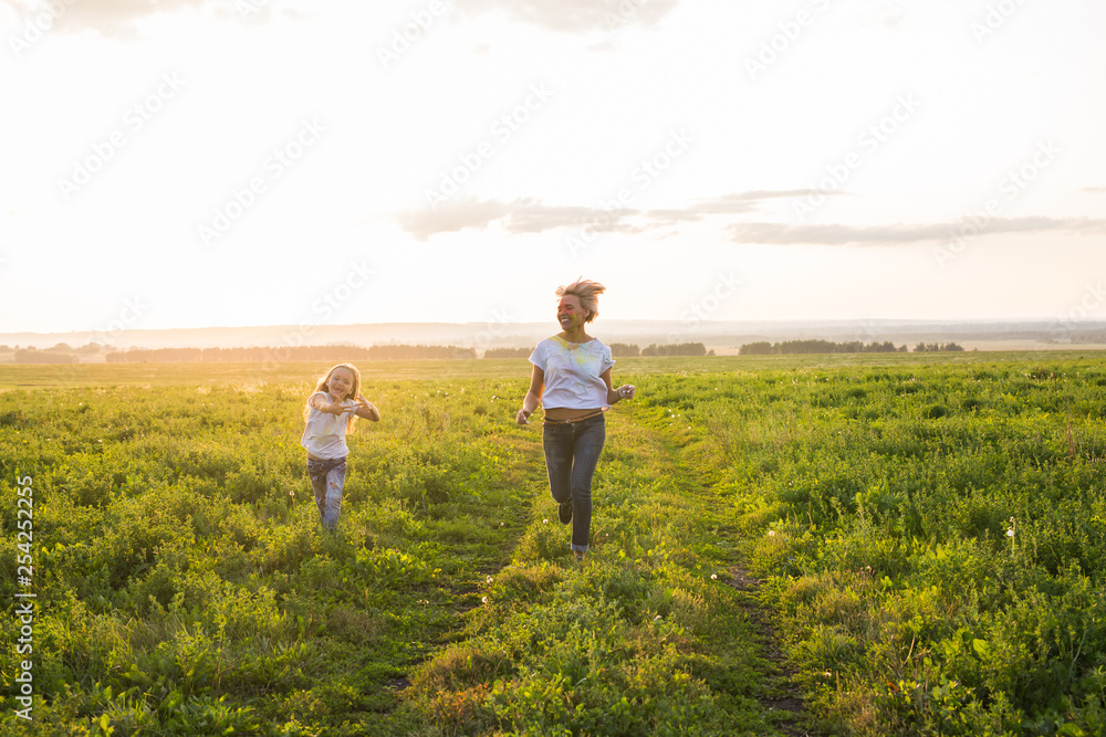 Family, summer and holiday concept - little daughter and mother run in the summer field