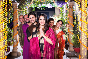 Family welcoming guests or in namaste / namaskara pose while looking at camera in celebration mood
