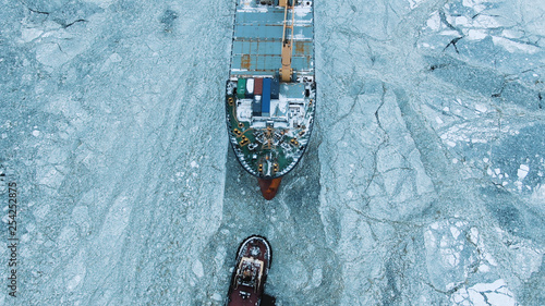 Aerial view. The big ship sails through the sea ice in the winter, close-up