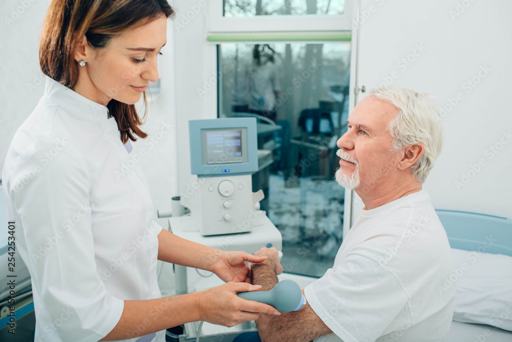 physiotherapist using ultrasound machine on hand of client in clinic. Physiotherapeutic treatment physiotherapist using ultrasound machine on hand of client in clinic. Physiotherapeutic treatment