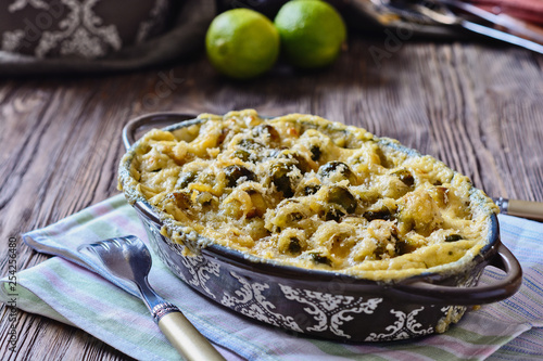 Delicious and healthy brussels sprouts baked in cream sauce with cheese and bread crumbs on a wooden table next to fork ready to eat