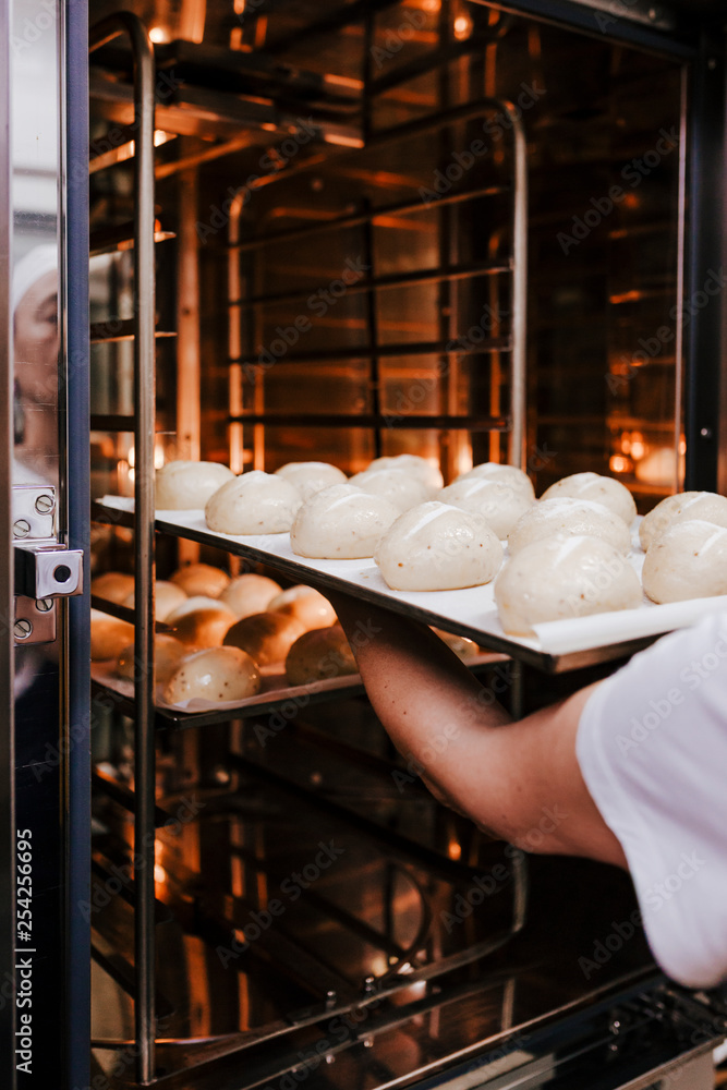 woman introducing bread baking in oven. Production oven at the bakery. Baking bread. Manufacture of bread woman introducing bread baking in oven. Production oven at the bakery. Baking bread. Manufacture of bread