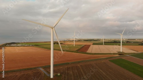 Windturbines during sunset in the south west of the Netherlands. Dynamic aerial shots with sun light. Flying away from subject, high above ground. photo