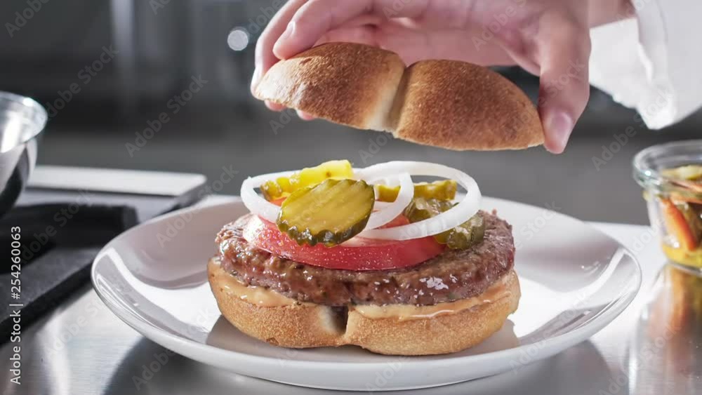 Cheff putting top whole grain bun on burger slow motion Cheff putting top whole grain bun on burger slow motion