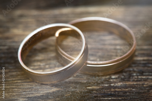 Pair of gold wedding rings on the wooden table background.