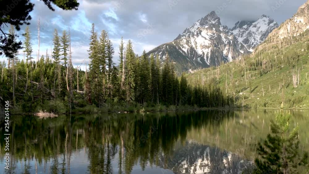 Slow right pan above Jenny Lake with pine tree and mountain reflection in Grand Teton National Park, Wyoming Slow right pan above Jenny Lake with pine tree and mountain reflection in Grand Teton National Park, Wyoming