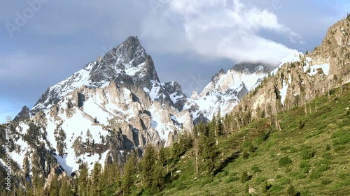 Clouds flowing off of the snow capped peaks in Grand Teron National Park, Wyoming photo