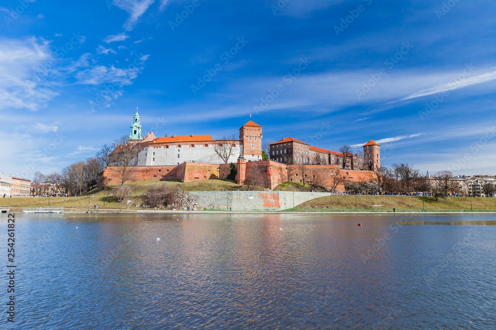 POLAND, KRAKOW - FEBRUARY 23, 2019: Wawel Castle, a view from the Vistula River. Blue sky and cloud. Gothic cathedral Polish architecture. POLAND, KRAKOW - FEBRUARY 23, 2019: Wawel Castle, a view from the Vistula River. Blue sky and cloud. Gothic cathedral Polish architecture.
