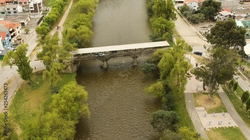 Aerial shot of a covered bridge with crossing cars over Rio Sta Barbara in Gualaceo in Ecuador. photo