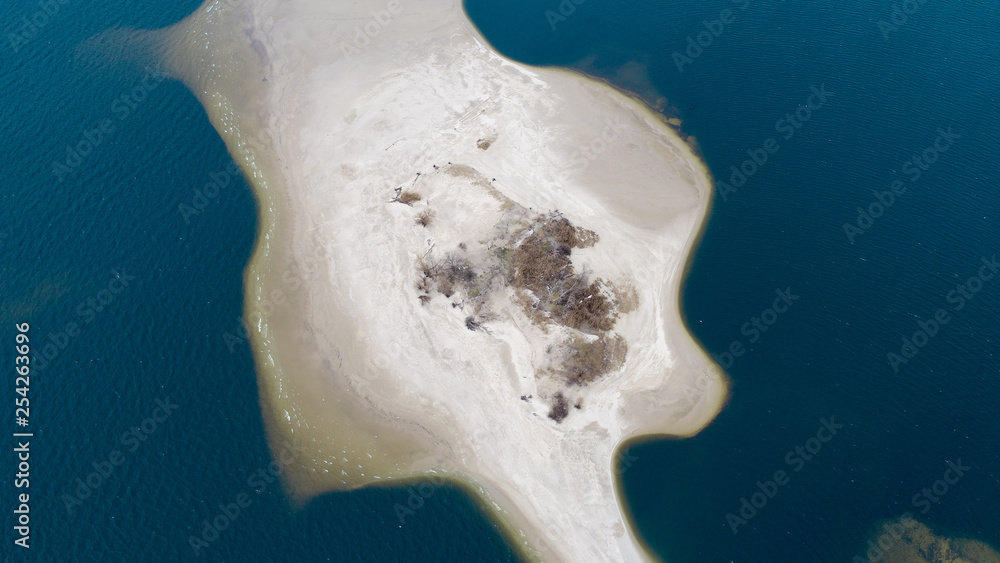 Fototapeta premium Little sand island in blue sea with lot of bold tress , areal view 