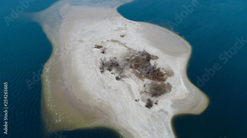 Little sand island in blue sea with lot of bold tress , areal view 