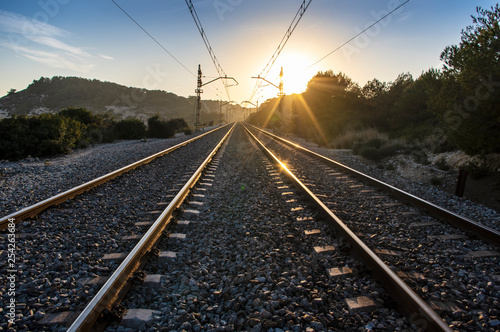 Train tracks at sunset with bright sun and metal reflections