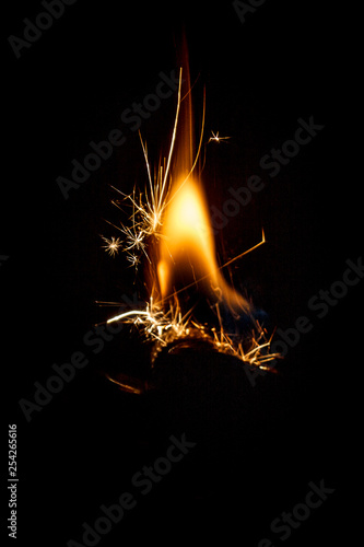 сlose-up of fire flame with sparks from the gas pocket lighter in different shapes isolated on a black background.  concept of stopping and freezing the moment.