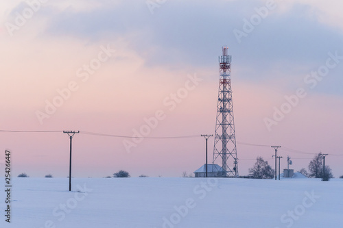 Transmission tower in winter  Telecommunications tower with cellular antenna and satellite dish