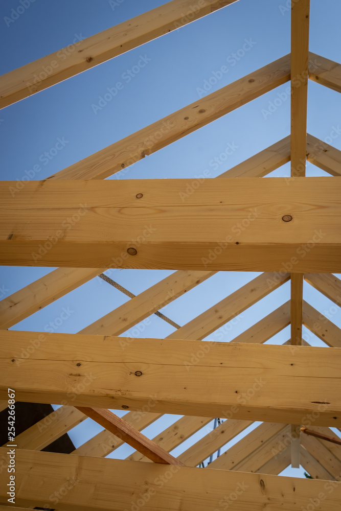 Holzbalken und Holzsparren lassen ein neues Hausdach erkennen Holzbalken und Holzsparren lassen ein neues Hausdach erkennen