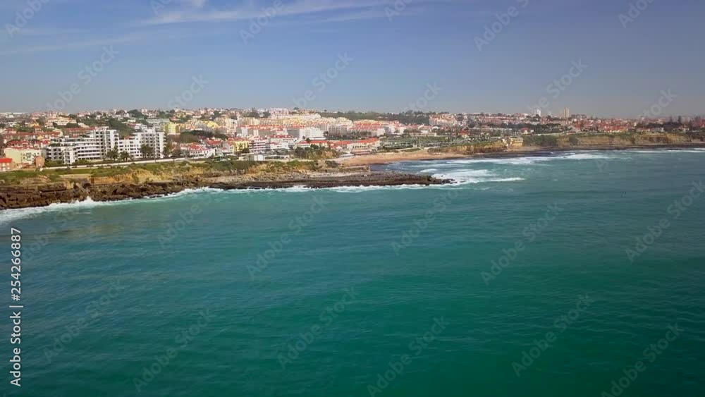 Aerial, drone shot, towards Praia de Sao pedro do Estoril, waves hitting rocks, on the Portuguese coast, on a sunny day, in Cascais, Portugal Aerial, drone shot, towards Praia de Sao pedro do Estoril, waves hitting rocks, on the Portuguese coast, on a sunny day, in Cascais, Portugal