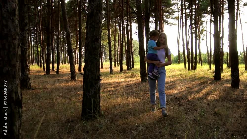 Sunset sun ray shine through evergreen forest as cute little family has nice relaxing evening walk in slow motion Sunset sun ray shine through evergreen forest as cute little family has nice relaxing evening walk in slow motion
