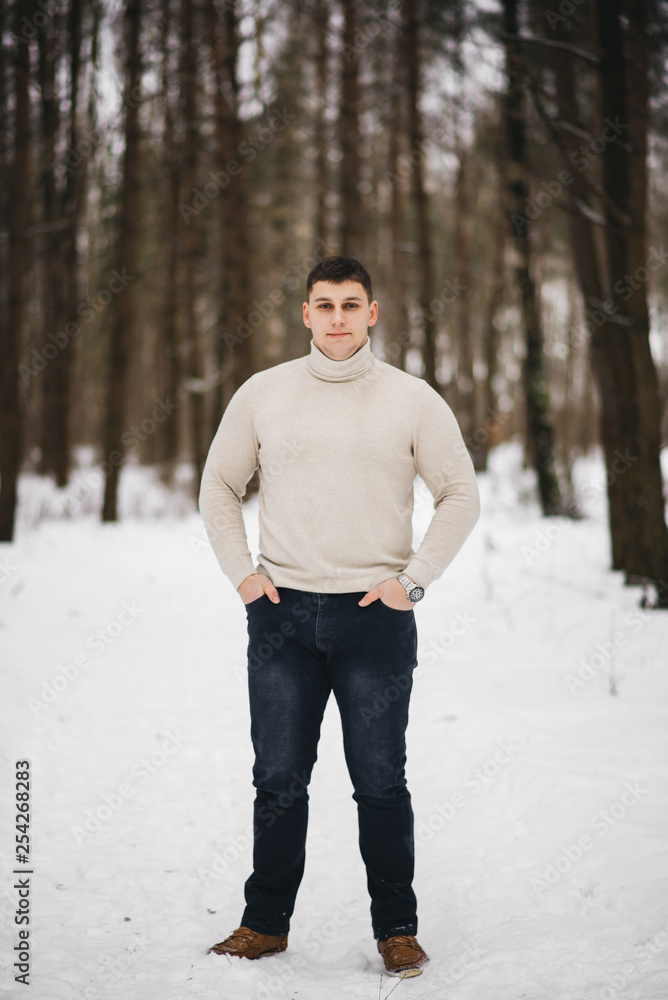 Portrait of a stylish young man on the background of a snowy forest Portrait of a stylish young man on the background of a snowy forest