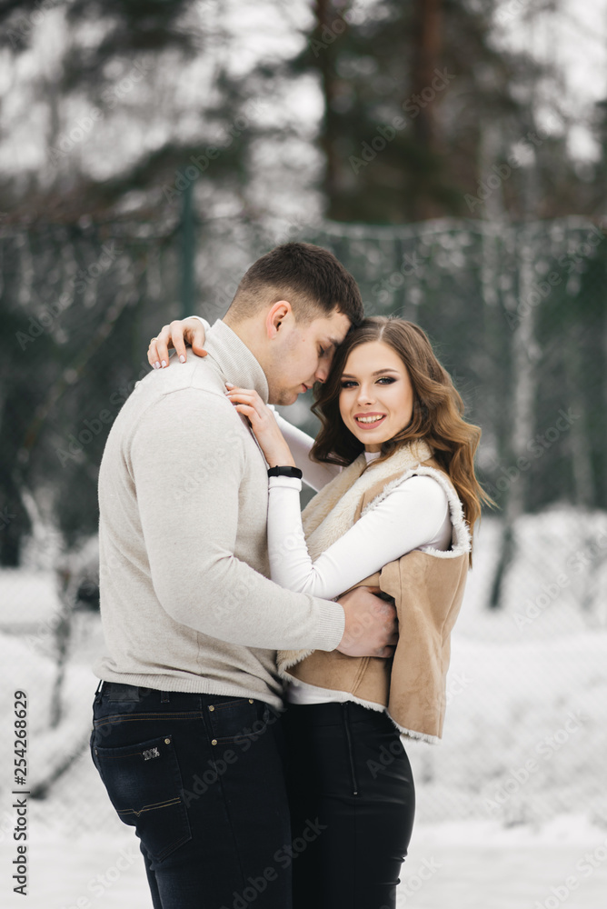 Fototapeta premium Winter love story on ice. Beautiful young guy and girl skating on ice