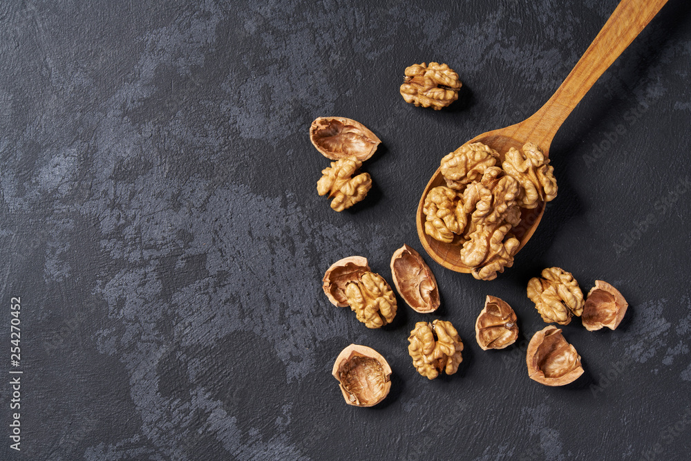 Walnut in wooden spoon on black table, with copy space. Top view. Walnut in wooden spoon on black table, with copy space. Top view.