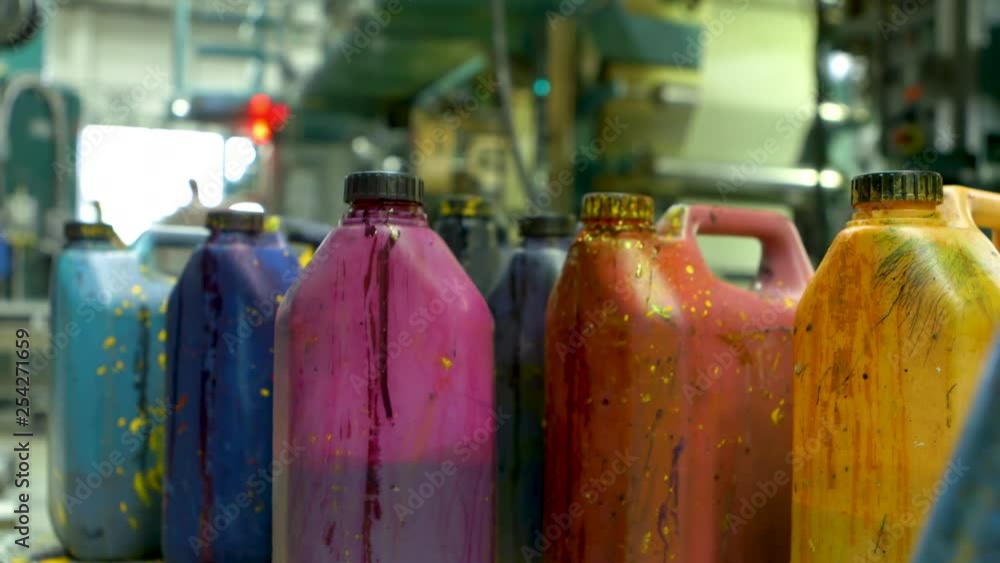 Closeup of a group of paint-splatterd containers. A male hand appears and places a violet container among the other containers. Closeup of a group of paint-splatterd containers. A male hand appears and places a violet container among the other containers.