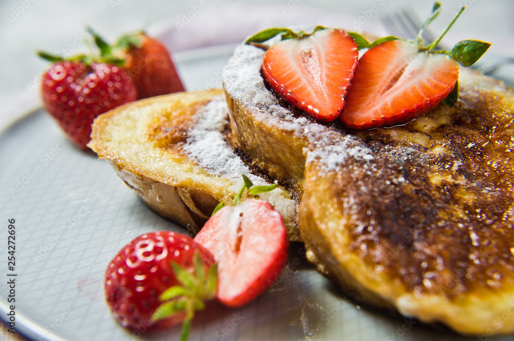 Toast with strawberries and maple syrup. Gray background, side view, close-up