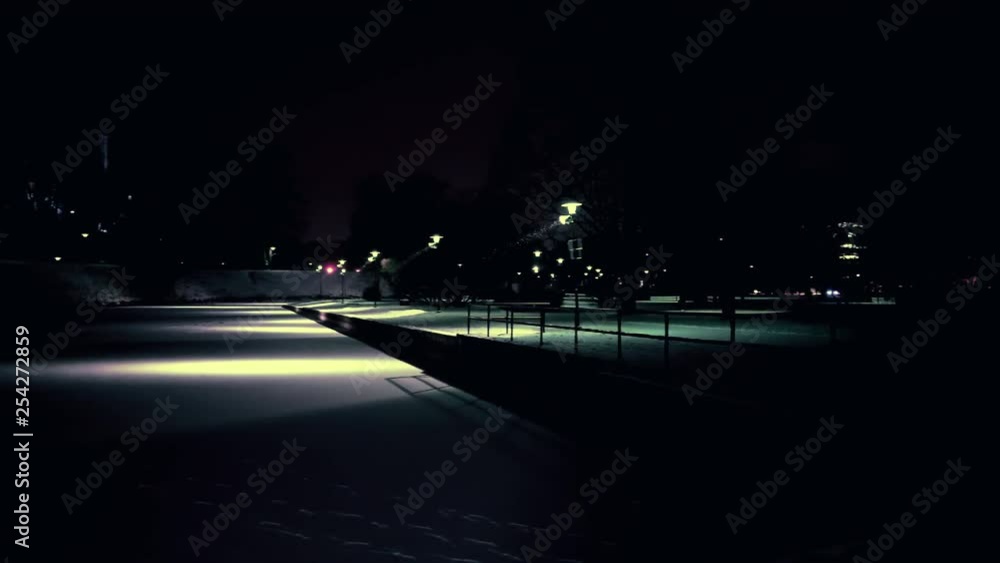 Pan shot of frozen pond covered with snow in a city park with traffic in background Pan shot of frozen pond covered with snow in a city park with traffic in background