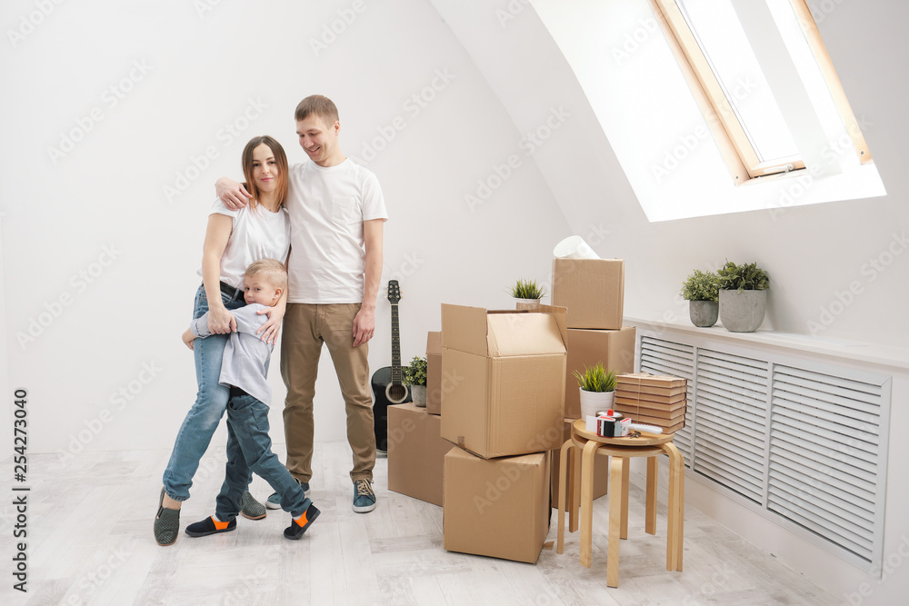 Young family, man woman and child son in new apartments. Boxes with cargo on a white background. Young family, man woman and child son in new apartments. Boxes with cargo on a white background.