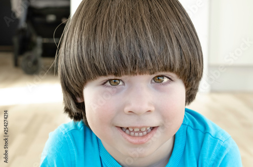Small boy with long hair is smiling and looking to the camera