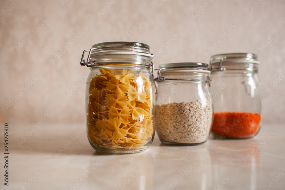 three glass jars with pasta, lentils, oatmeal on a white background three glass jars with pasta, lentils, oatmeal on a white background