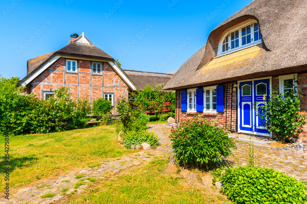 Traditional house with straw roof and sunny blue sky in Middelhagen village, Ruegen island, Baltic Sea, Germany