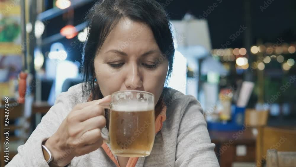 Close up of caucasian woman drinking beer at the street cafe in the evening. Close up of caucasian woman drinking beer at the street cafe in the evening.