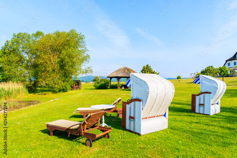 Wicker chairs in green area along lake shore in Seedorf village, Baltic Sea, Germany Wicker chairs in green area along lake shore in Seedorf village, Baltic Sea, Germany